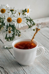 a bouquet of daisies and tea on a white wooden table