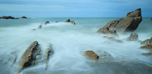 Rocks surrounded by blurred sea waves in coastal town of Ilfracombe, Devon