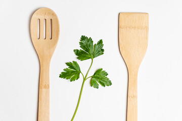 .a sprig of green parsley between a bamboo spoon and a scapula