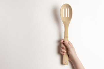 .Bamboo spoon in a children's hand on a white background. A child is holding a bamboo spoon - top...