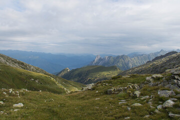 The view of slope with green grass and mountains on background, Braone Valley, Italy.