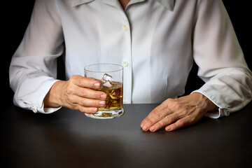 close-up of a woman's hands with a glass of Scotch and ice