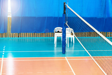 Modern empty school gym indoor with volleyball net, referee chair with scoring Board