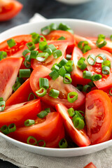 Tomato salad with spring onion and herbs in white bowl. Healthy summer food