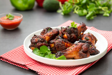 Roasted chicken legs, drumsticks on plate with fresh vegetables.