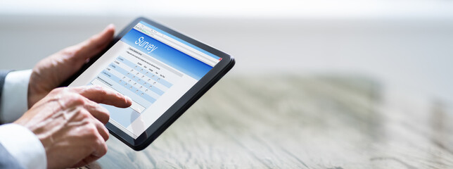 Man Filling Online Survey Form On Digital Tablet