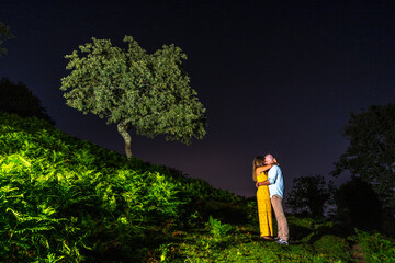 A couple embraced on the warm night of Mount Erlaitz in the town of Irún, Guipuzcoa. Basque Country. Night photography in June, lightpainting