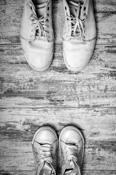 Big and small shoes on wooden background. Still life photography : father and child shoes on old wood in vintage color tone, go ahead together and fathers day concept.