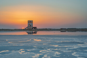 Obraz premium Sole che tramonta dietro la torre di Nubia, Saline di Trapani IT