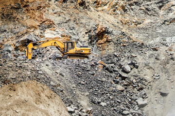 Heavy machinery, industrial excavator digging for granite rocks at quarry