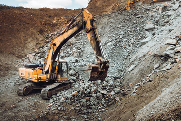 Industrial track type excavator digging at a quarry or a construction site, machinery details.