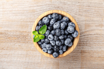 Juicy and fresh blueberries with green leaves on rustic table. Blueberry antioxidant.