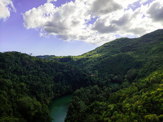 Fototapeta na wymiar a mountain river among thick green hills on which the sun falls