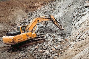 Hydraulic crusher and track type excavator backhoe machinery working on site demolition and construction site.