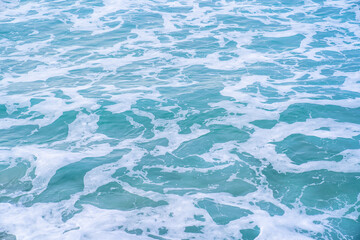 Soft blue ocean wave on sandy beach. Background textured.