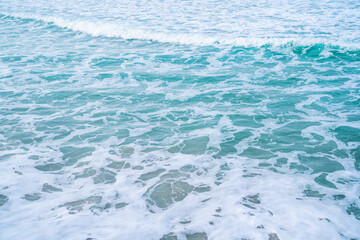 Fototapeta na wymiar Soft blue ocean wave on sandy beach. Background textured.