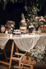 Candy bar. White wedding cake decorated by flowers standing of festive table with deserts, strawberry tartlet and cupcakes. Wedding. Reception Tartlets