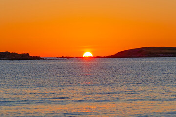The fiery red skies as the sun sets on Plage Sainte-Marguerite at the end of a summers day in Brittany
