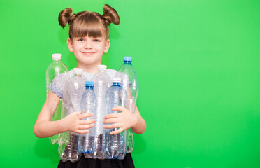 Photo of funny little girl holding plastic bottles and looking at camera isolated over green background