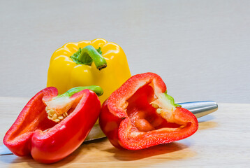 Red paprika cut in half leaning against a yellow paprika