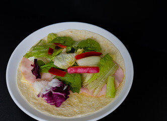 Ham, mozzarella cheese, lettuce  and bell pepper slices on flour tortilla