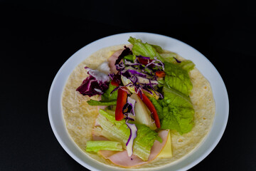 Ham, mozzarella cheese, lettuce  and bell pepper slices on flour tortilla