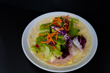 Ham, mozzarella cheese, lettuce  and bell pepper slices on flour tortilla