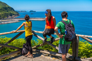 Three friends looking from the viewpoint at the Orio coast, gipuzkoa, basque country. Excursion...