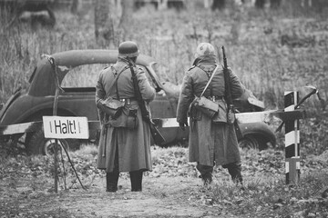 Unidentified Re-enactors Dressed As German Infantry Wehrmacht soldier at World War II are on patrol in autumn field.
