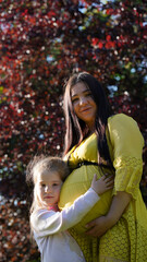 Portrait of a pregnant woman with daughter in the park