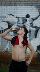 Young man drinking refreshing water after basketball on playground