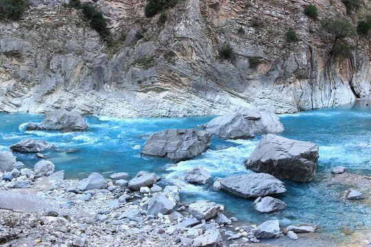 Rushing river with blue water between big rocks into a gorge
