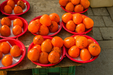 Persimmons in red plastic bowls
