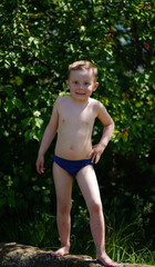 Portrait of a funny little boy standing barefoot outdoors