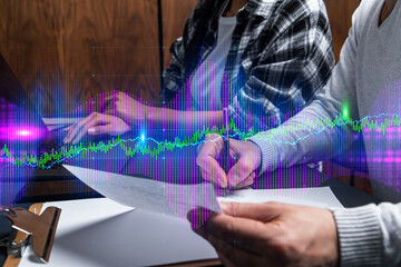 Fototapeta premium Two business people working together on stock market strategy. Try to analyze forex behavior. Financial graph hologram. Double exposure.