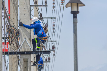Electricians are climbing on electric poles to install and repair power lines.