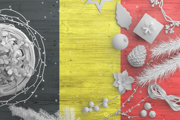 Belgium flag on wooden table with snow objects. Christmas and new year background, celebration national concept with white decor.