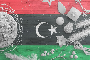 Libya flag on wooden table with snow objects. Christmas and new year background, celebration national concept with white decor.