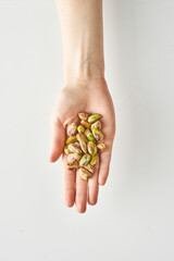 100 calories of healthy snack of pistachios in hand isolated on a white background, healthy food and lifestyle