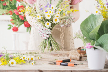 girl florist makes  bouquet of wildflowers