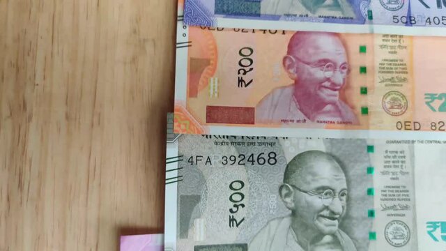 Closeup of brand new colorful Indian currency bank notes of 10, yellow 20, 50, purple 100, 200, 500 and pink 2000 rupees bundle issued and in circulation after demonetisation against wooden background