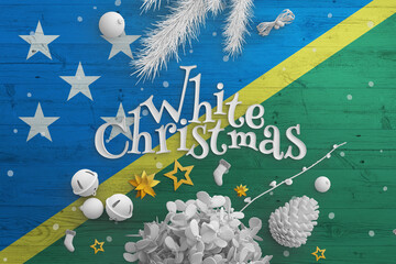 Solomon Islands flag on wooden table with White Christmas text. Christmas and new year background,...