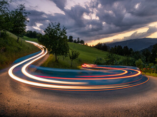 Curvy serpentine road through Austrian Alps mountains. Long exposure showing the movement of...