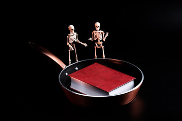 two skeletons are talking on the background of the book lying on the pan