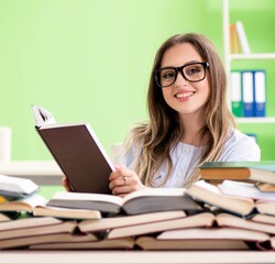 Young female student preparing for exams with many books