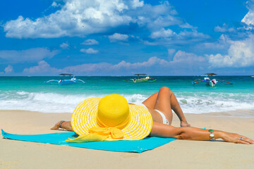 Woman in yellow bikini lying on tropical beach