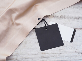 black paper sale tag hanging on silk cloth over white vintage wood background.