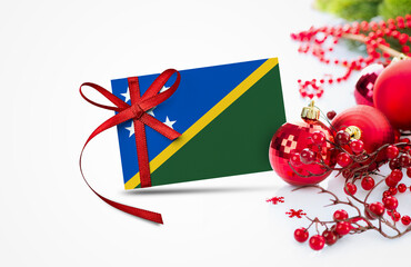 Solomon Islands flag on new year invitation card with red christmas ornaments concept. National...