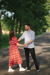 Beautiful couple walking in park. Happy young female with handsome man dancing outdoors