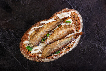 Sandwich with sprots on rye bread lies on a concrete background